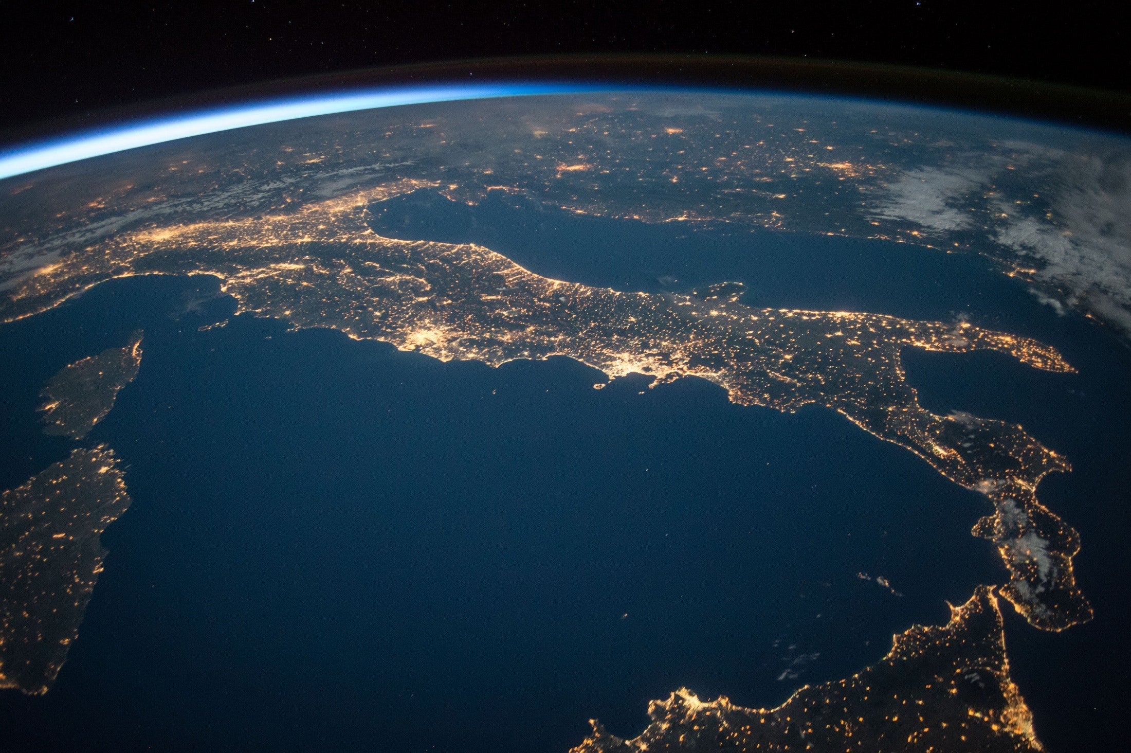 A picture taken from space of Earth, specifically the Italian peninsula at night, representing the distributed network that comes with edge computing and edge caching which load balances duplicative requests of static web content.