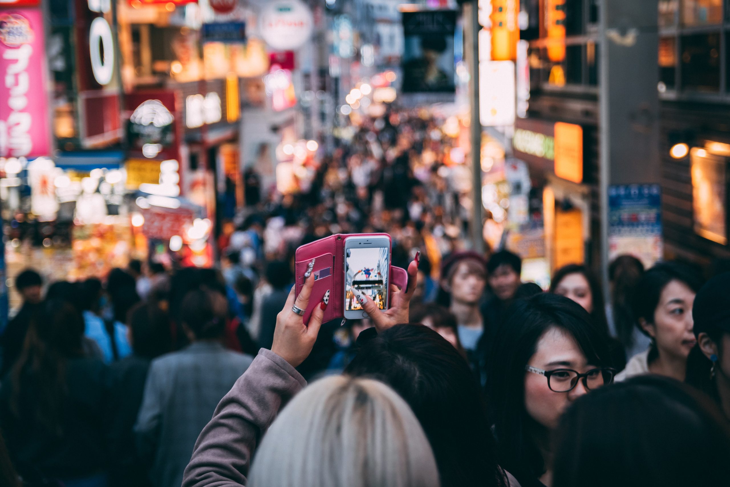 What is Edge Networking? A picture of a person holding a phone in a crowded area, representative of the type of edge computing needed for the next generation of connectivity and IoT devices.
